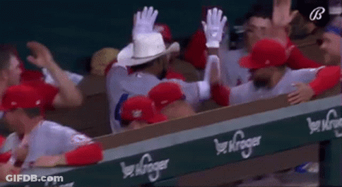 A Group Of Baseball Players Are Sitting In A Dugout . GIF