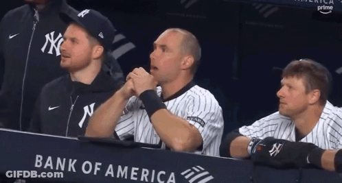 A Group Of Baseball Players Are Sitting In A Dugout With A Bank Of America Banner Behind Them GIF
