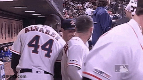 A Group Of Baseball Players Are Standing In A Dugout And One Of Them Has The Number 44 On His Back . GIF