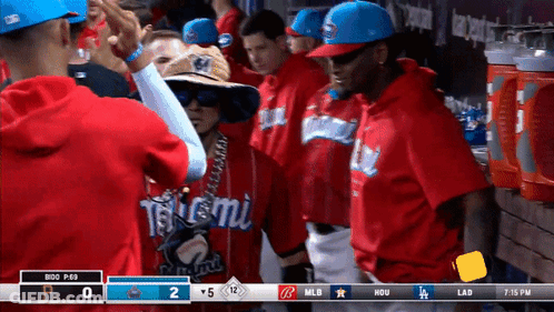 A Group Of Baseball Players Are Standing In A Dugout With A Scoreboard That Says MLB At The Top GIF