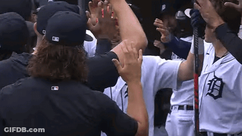 A Group Of Baseball Players Are Standing In A Huddle And Giving Each Other A High Five . GIF