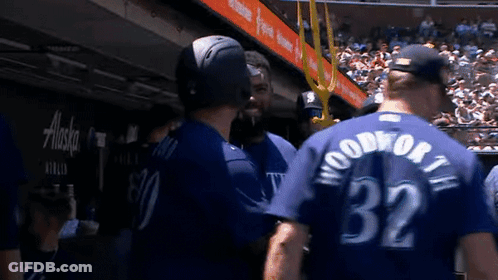 A Group Of Baseball Players Are Standing Next To Each Other In A Dugout . GIF