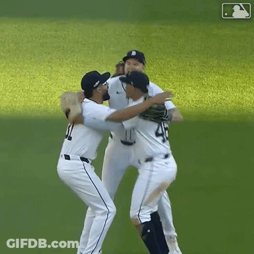 A Group Of Baseball Players Hugging Each Other On The Field GIF