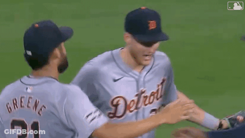 A Group Of Baseball Players Hugging Each Other On The Field GIF