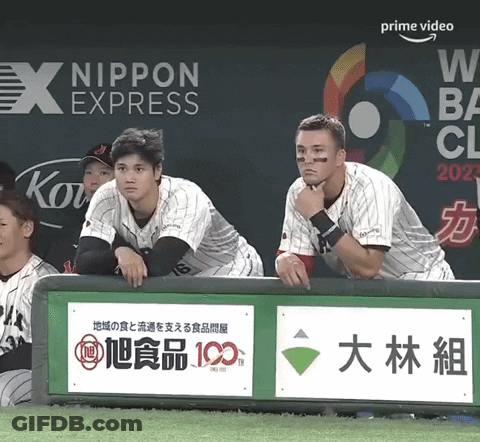 A Group Of Baseball Players Sitting In The Dugout With An Ad For Nippon Express Behind Them GIF