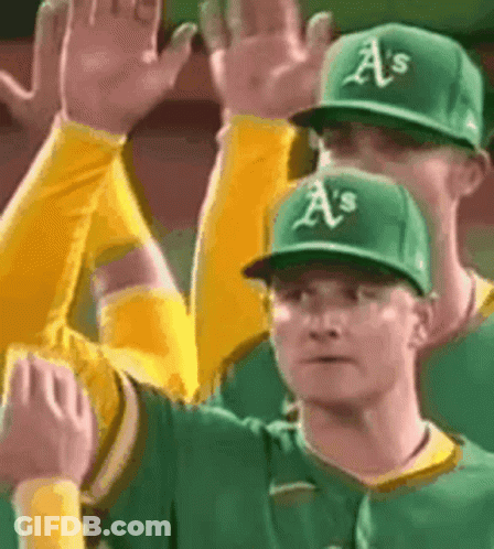 A Group Of Baseball Players Wearing Green And Yellow Uniforms Are Giving Each Other A High Five . GIF