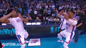 A Group Of Basketball Players Are Dancing On A Court In Front Of A Crowd GIF