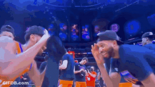 A Group Of Basketball Players Are Huddled Together In A Stadium . GIF