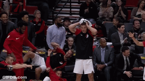 A Group Of Basketball Players Are Playing A Game And One Of Them Is Holding His Head In His Hands . GIF