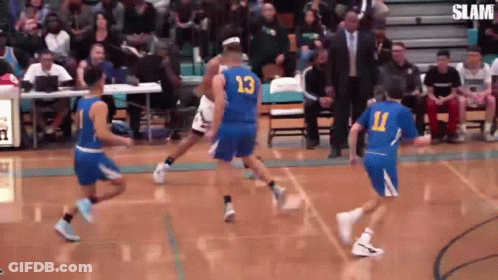 A Group Of Basketball Players Are Playing A Game On A Court With A Crowd Watching . GIF