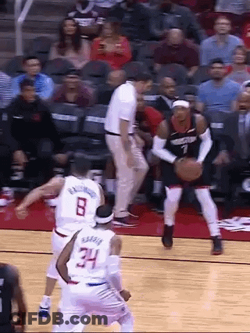 A Group Of Basketball Players Are Playing A Game On A Court With A Referee In The Background . GIF