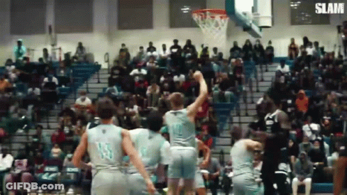 A Group Of Basketball Players Are Playing Basketball In Front Of A Crowd . GIF