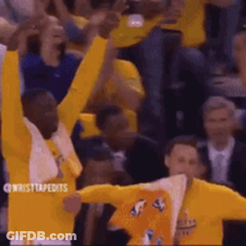 A Group Of Basketball Players Are Raising Their Arms In The Air While A Crowd Watches . GIF