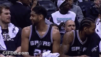 A Group Of Basketball Players Are Sitting In A Stadium . GIF