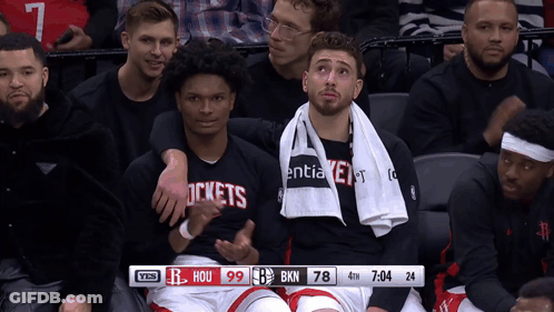 A Group Of Basketball Players Are Sitting In A Stadium With A Scoreboard That Says Hou 99 Bkn 78 GIF
