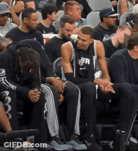 A Group Of Basketball Players Are Sitting In The Stands And One Of Them Is Wearing A Shirt That Says Spurs GIF