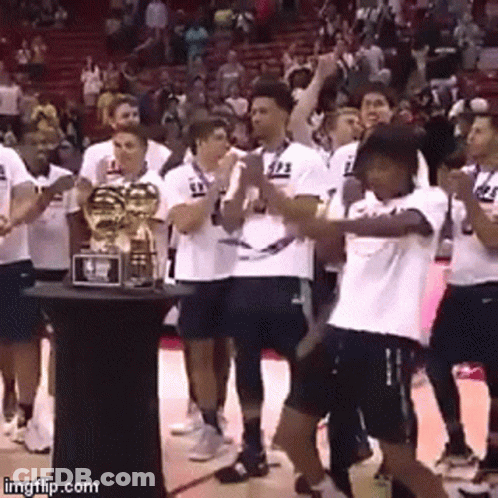 A Group Of Basketball Players Are Standing Around A Trophy With The Number 23 On Their Shirts GIF