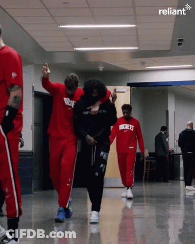 A Group Of Basketball Players Are Walking Down A Hallway And One Of Them Is Wearing A Rockets Shirt GIF
