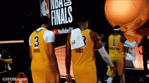 A Group Of Basketball Players Standing In Front Of A Sign That Says Finals GIF
