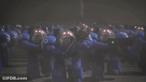 A Group Of Blue Robots With Red Lights On Their Faces Are Standing Next To Each Other . GIF