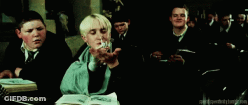 A Group Of Boys Are Sitting At A Table In A Classroom And One Of Them Is Holding A Book . GIF