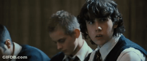 A Group Of Boys Are Sitting In A Classroom And One Of Them Has Curly Hair GIF