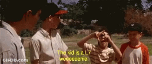 A Group Of Boys Are Standing In A Field With One Saying The Kid Is A L7 Weeeeenie GIF