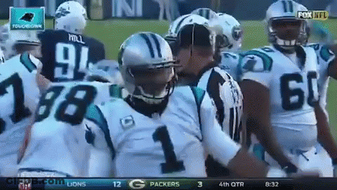 A Group Of Carolina Panthers Football Players Are Huddled Around A Referee GIF
