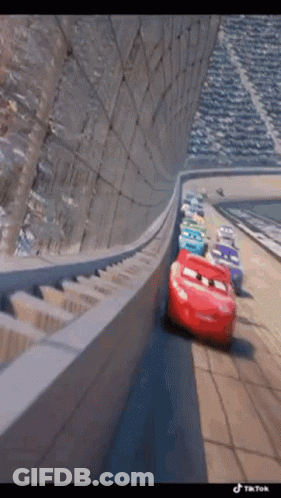 A Group Of Cars Are Driving Down A Race Track . GIF