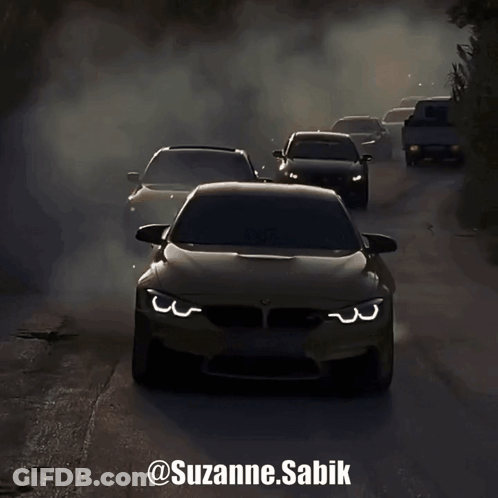 A Group Of Cars Driving Down A Road With Smoke Coming Out Of Their Tires GIF