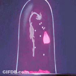 A Group Of Cartoon Characters Are Standing Around A Table With A Statue On Top Of It GIF