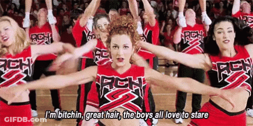 A Group Of Cheerleaders Are Dancing On A Basketball Court With Their Arms Outstretched In Front Of A Crowd . GIF