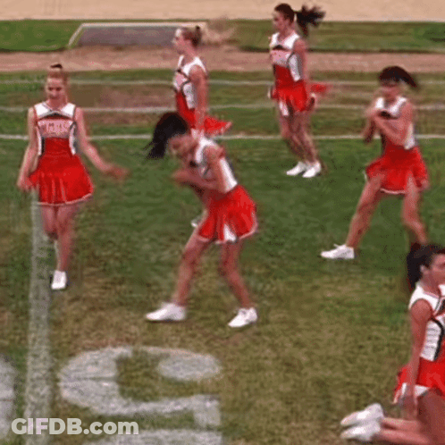 A Group Of Cheerleaders Are Dancing On A Field While Another Cheerleader Sits On The Ground . GIF