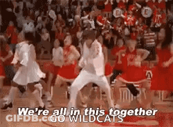 A Group Of Cheerleaders Are Dancing Together On A Basketball Court While A Crowd Watches . GIF