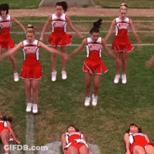 A Group Of Cheerleaders Are Performing On A Field And One Of Them Is Wearing A Hhs Uniform GIF