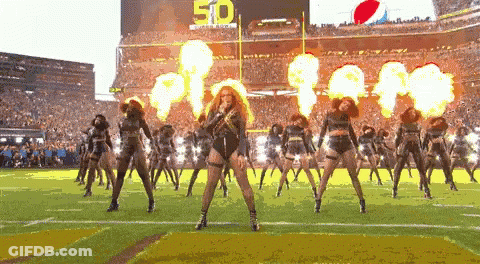 A Group Of Cheerleaders Are Performing On A Football Field In Front Of A Scoreboard With The Number 50 On It GIF