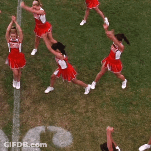 A Group Of Cheerleaders Are Sitting On The Grass In Front Of The Letter C. GIF