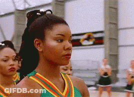 A Group Of Cheerleaders Are Standing In A Line And One Of Them Is Wearing A Green And Yellow Uniform GIF