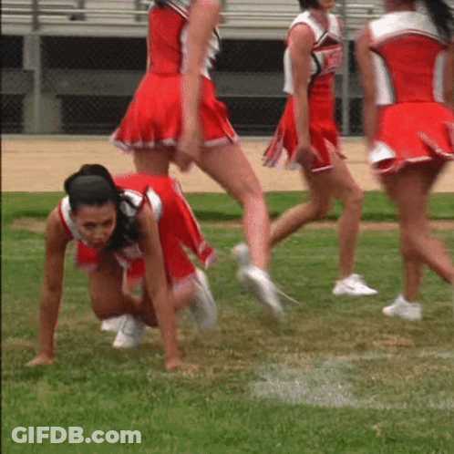 A Group Of Cheerleaders In Red Uniforms Are Crawling On The Field GIF