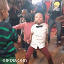 A Group Of Children Are Dancing In A Room With Adults . GIF