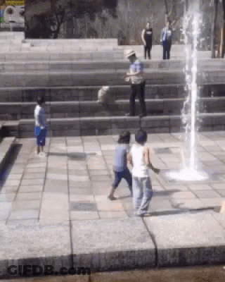 A Group Of Children Playing In Front Of A Water Fountain GIF
