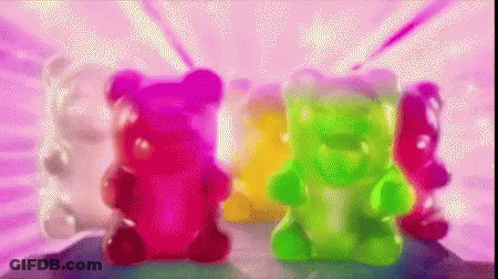 A Group Of Colorful Gummy Bears Are On A Pink Background GIF