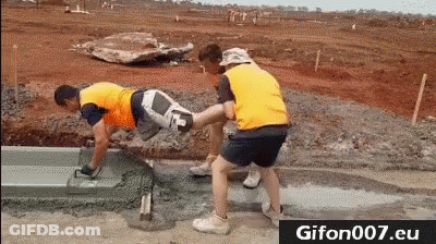 A Group Of Construction Workers Are Laying Concrete On A Road . GIF