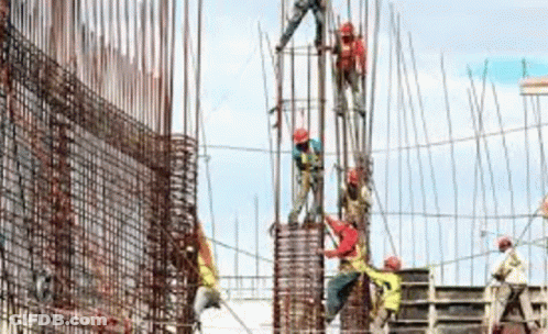 A Group Of Construction Workers Are Working On A Large Building . GIF