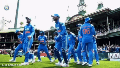 A Group Of Cricket Players Are Walking On A Field In Front Of A Building With The Number 96 On Their Jersey . GIF