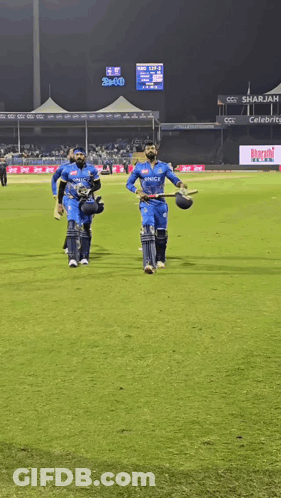 A Group Of Cricket Players Are Walking On A Field With A Scoreboard In The Background That Says Bcci GIF