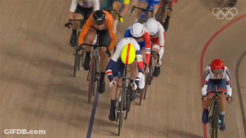 A Group Of Cyclists Are Racing On A Track With The Olympic Rings Visible In The Background GIF