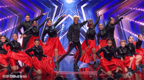 A Group Of Dancers Are Performing On A Stage And They Are Wearing Red Skirts . GIF