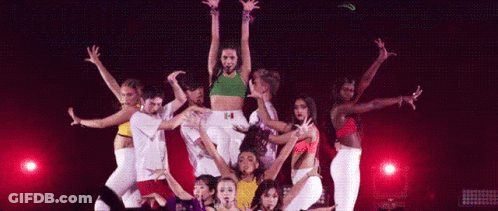 A Group Of Dancers Are Performing On A Stage With A Woman Standing In The Middle . GIF