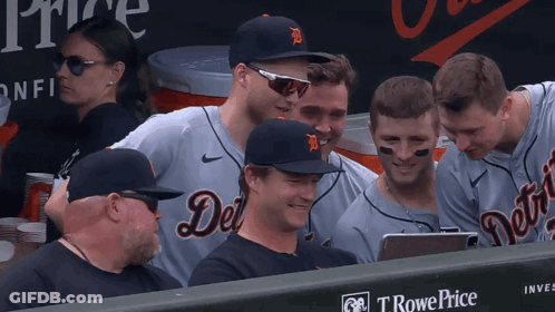A Group Of Detroit Tigers Players Are Sitting In The Dugout Looking At A Tablet GIF